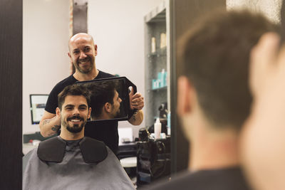 Barber holding mirror while showing to customer in salon