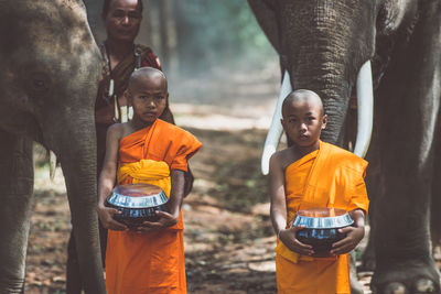 Monks standing with elephant in forest