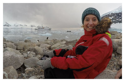 Portrait of smiling young woman in sea during winter