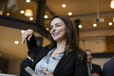 Low angle view of smiling businesswoman gesturing in conference center