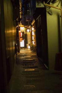 Empty alley amidst buildings in city at night