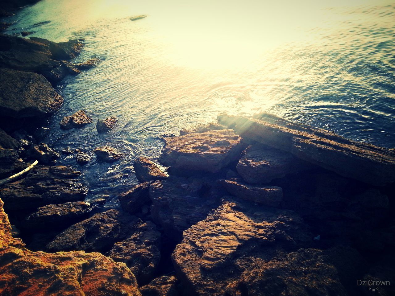 water, high angle view, reflection, sea, nature, sunlight, tranquility, outdoors, beauty in nature, river, stone - object, rock - object, lake, rippled, tranquil scene, day, scenics, no people, beach, shore