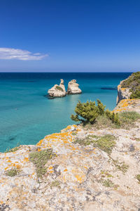 Scenic view of rocks in sea against blue sky