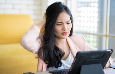 Young woman looking at camera while sitting in laptop