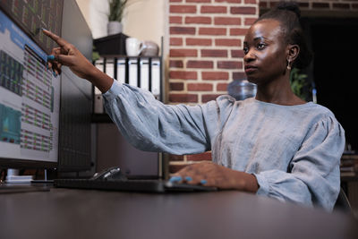 Young businesswoman analyzing graph on computer