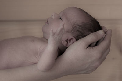 Cropped hands of father holding sleeping baby at home