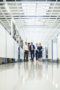 Businessman with colleagues discussing over tablet computer in corridor