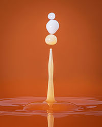 Close-up of water drops on glass against orange background