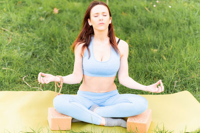 Full length of a young woman sitting on grass