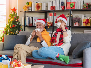 Friends using phone while sitting on sofa at home