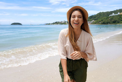 Portrait of young woman standing at beach