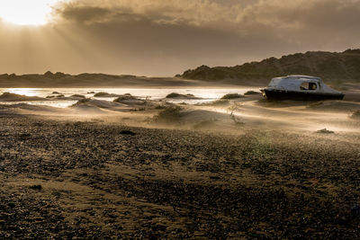 Cars on sea against sky during sunset