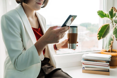 Break time in the office. close up of businesswoman hands with coffee mug and cell phone at the