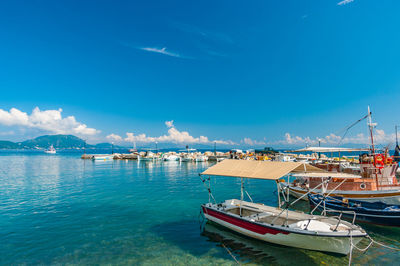 Sailboats moored at harbor against blue sky