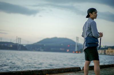 Portrait asian man standing on the port and looking out to the sea with the twilight sky of sunset