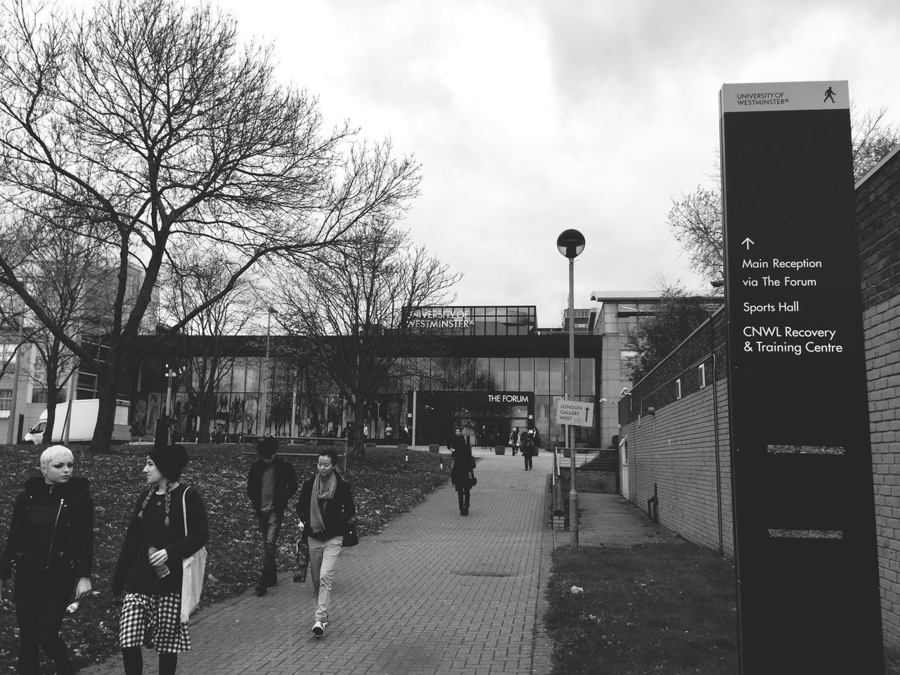 building exterior, architecture, built structure, sky, tree, text, city, men, communication, bare tree, western script, street, walking, lifestyles, information sign, cloud - sky, sign, person, street light