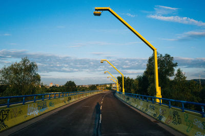 Road by trees against sky