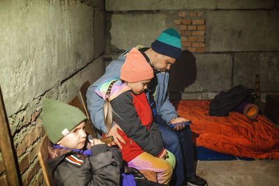 Ukrainian father with kids sits in bomb shelter and reads latest braking news about russian invaders