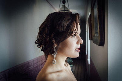 Young woman wearing lipstick and earrings at home