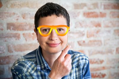 Portrait of smiling woman holding sunglasses prop