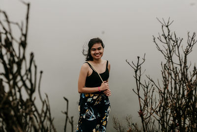 Happy young woman standing on land against sky