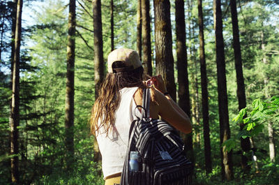 Woman with backpack standing in forest