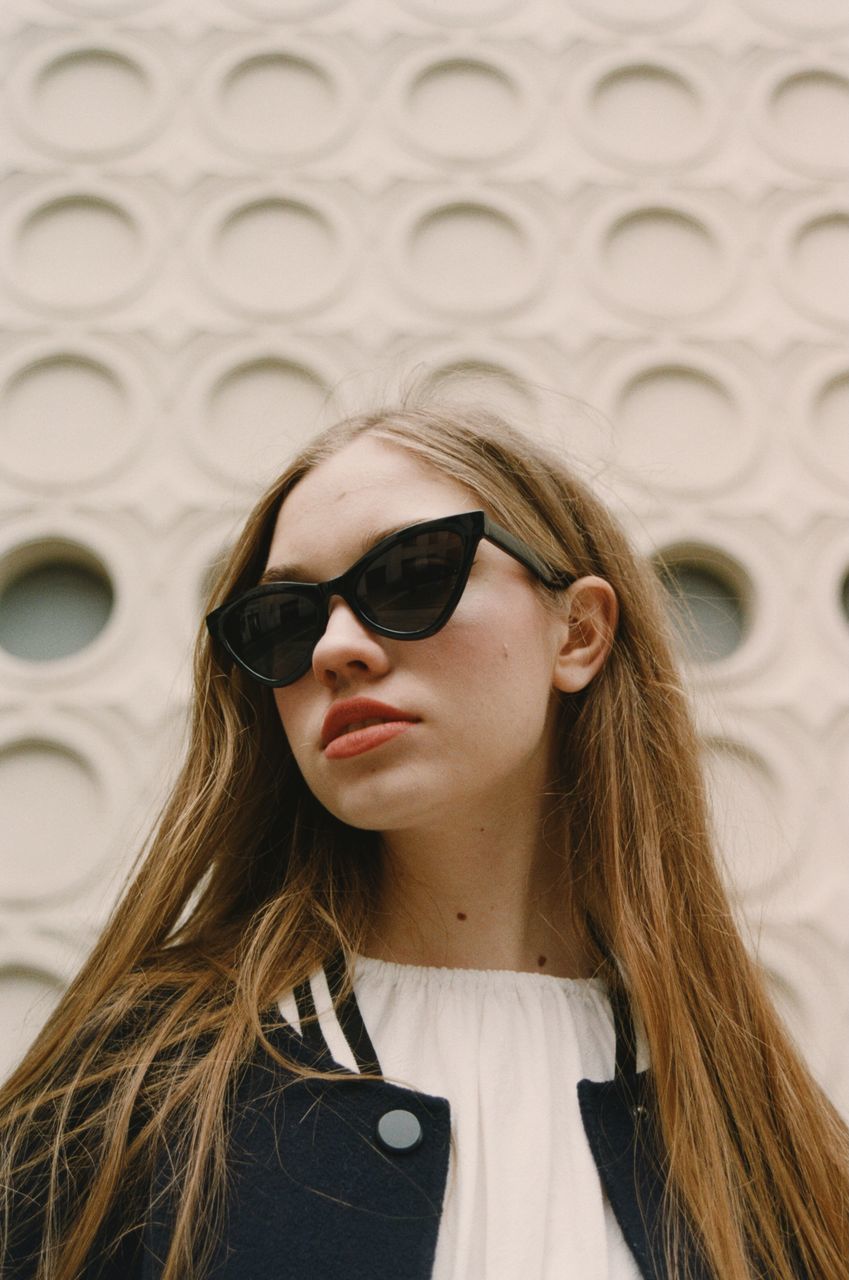 PORTRAIT OF BEAUTIFUL YOUNG WOMAN STANDING AGAINST WALL