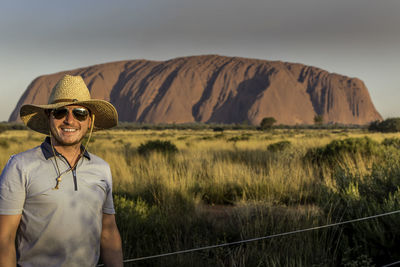 Portrait of smiling young man standing against mountains