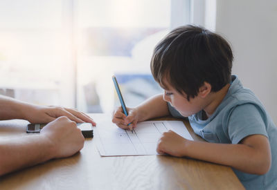 Cute boy writing on paper at home