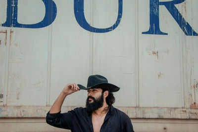 Man wearing hat against wall