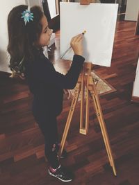Girl painting while standing on hardwood floor