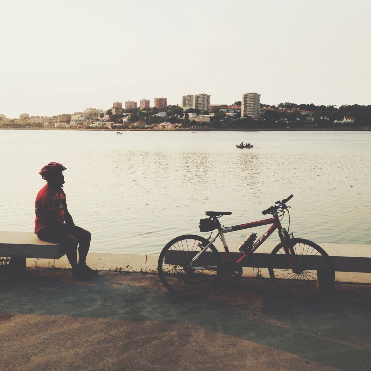 water, lifestyles, built structure, clear sky, architecture, building exterior, leisure activity, river, men, full length, transportation, sitting, city, mode of transport, rear view, copy space, casual clothing, nautical vessel