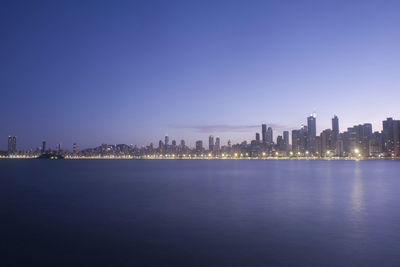 Sea by buildings against clear blue sky