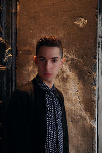 Portrait of young man standing against wall