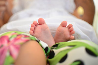 Low section of baby lying on bed