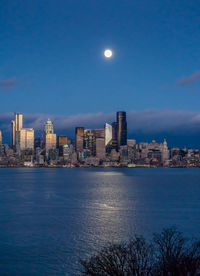 A bright full moon shines over the seattle skyline.