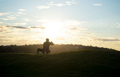 Man on field against sky during sunset