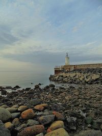 Lighthouse on the beach by sea against sky