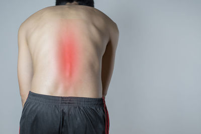 Rear view of shirtless man standing against white background