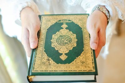 Midsection of woman holding holy quran