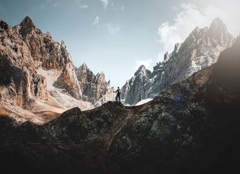 Rear view of man standing on snowcapped mountain against sky