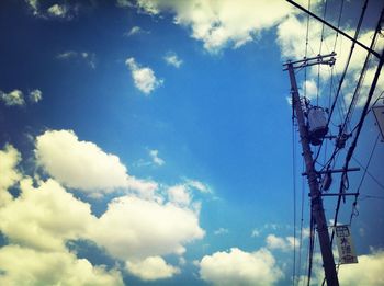 Low angle view of power lines against cloudy sky