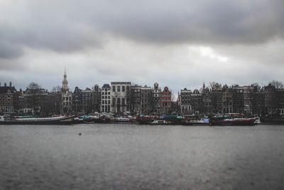 Sea by buildings against sky in city