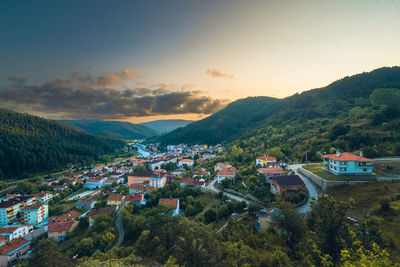 Houses amidst trees and buildings against sky during sunset