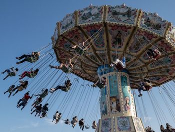 Low angle view of people enjoying chain swing ride against sky