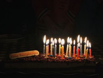 Close-up of burning candles on birthday cake in darkroom