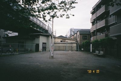 Empty road by buildings in city against sky