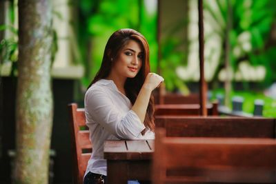 Portrait of young woman sitting on railing