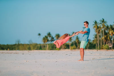 Side view of women on beach against clear sky