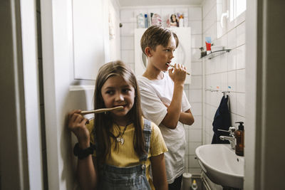 Siblings standing in bathroom at home